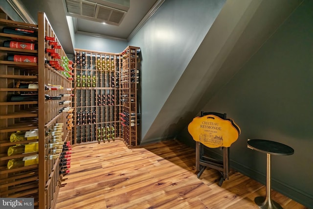 wine area featuring ornamental molding, wood finished floors, and visible vents