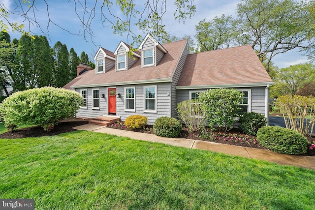 new england style home with a shingled roof and a front lawn