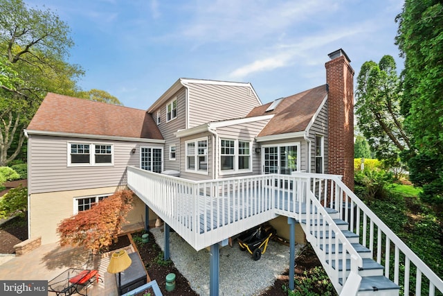 rear view of house with stairway, roof with shingles, a chimney, and a deck