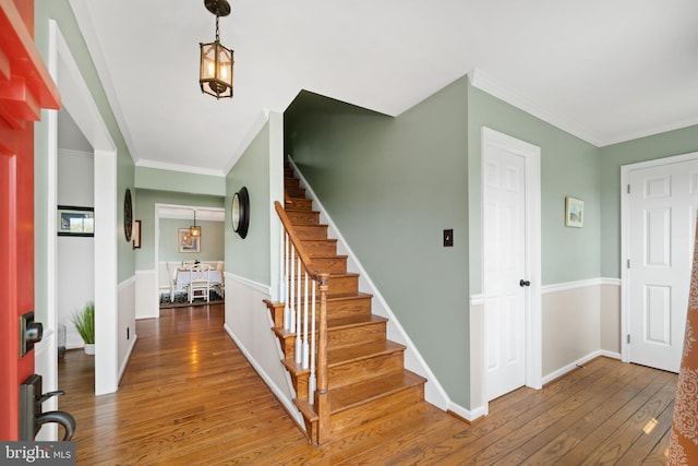 entrance foyer with wood-type flooring, ornamental molding, baseboards, and stairway