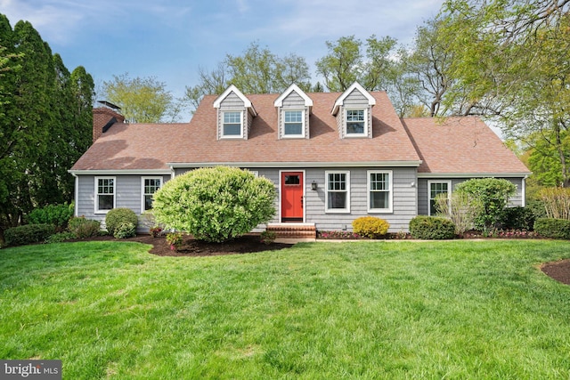 cape cod house featuring a shingled roof, a front lawn, and a chimney