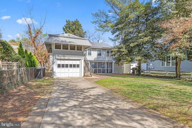 view of front of property featuring a sunroom, stairway, fence, a front lawn, and concrete driveway