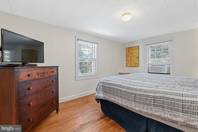 bedroom featuring light wood-type flooring, cooling unit, and baseboards