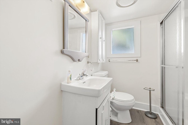 bathroom featuring toilet, a shower stall, vanity, and wood finished floors