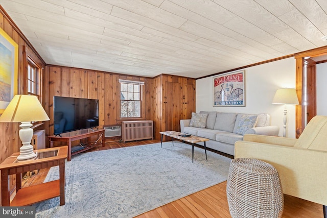 living area featuring wooden walls, radiator, and wood finished floors