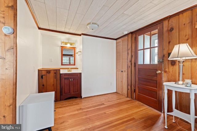 entrance foyer with ornamental molding, light wood-style floors, and wood ceiling