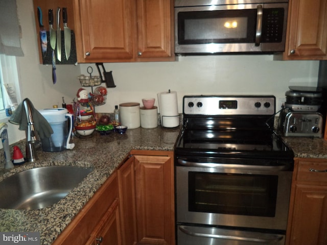 kitchen with a sink, appliances with stainless steel finishes, and brown cabinetry