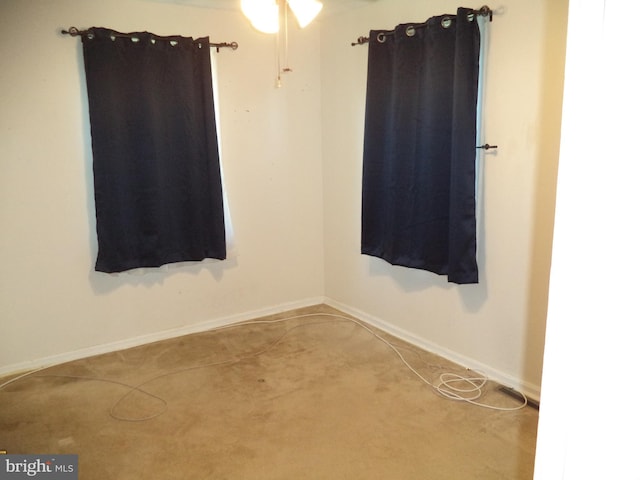 spare room with carpet floors, a ceiling fan, and baseboards