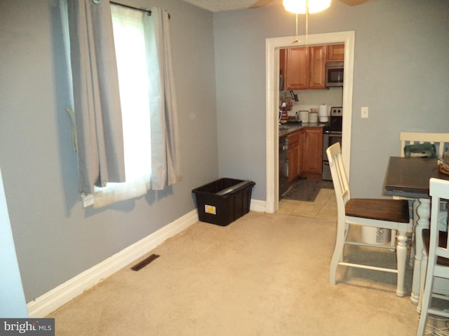 dining area featuring light colored carpet, ceiling fan, visible vents, and baseboards