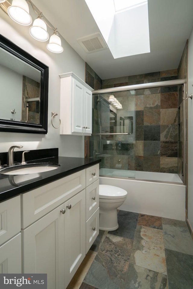 4501 Peppermill Ct, Dumfries, VA 22025 - full bathroom with vanity, toilet, shower / bath combination with glass door, stone finish flooring, and a skylight
