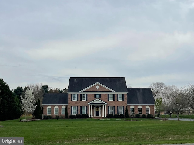 colonial home with a front lawn and brick siding