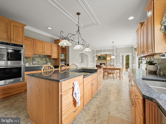 kitchen featuring double oven, tasteful backsplash, crown molding, and a center island