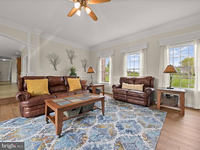 living room with hardwood / wood-style flooring, arched walkways, a ceiling fan, and crown molding