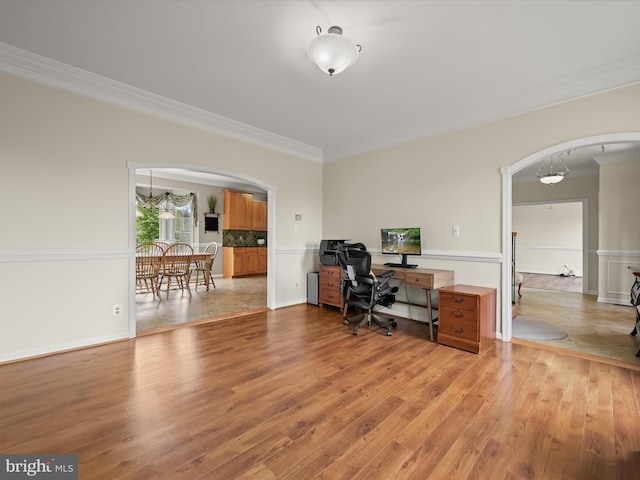 office with arched walkways, ornamental molding, and light wood-type flooring