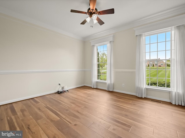 empty room with crown molding, plenty of natural light, baseboards, and wood-type flooring