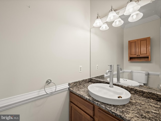 half bath featuring toilet, vanity, and ornamental molding