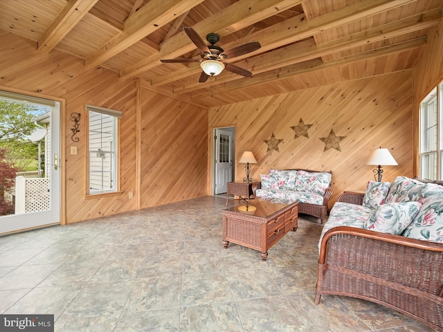 living area with beamed ceiling, a ceiling fan, wood walls, and wood ceiling