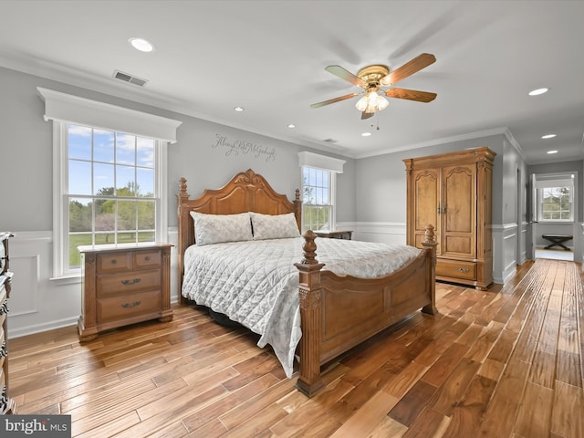 bedroom with crown molding, a wainscoted wall, light wood finished floors, visible vents, and recessed lighting