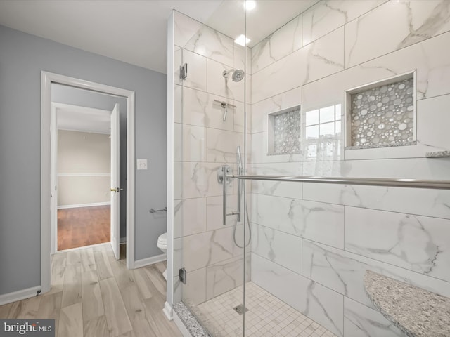 full bath featuring baseboards, toilet, a stall shower, and wood finished floors