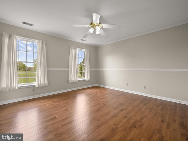 spare room featuring a ceiling fan, baseboards, dark wood-style flooring, and visible vents