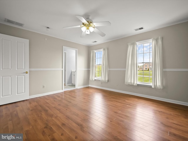unfurnished bedroom featuring hardwood / wood-style flooring, visible vents, and multiple windows