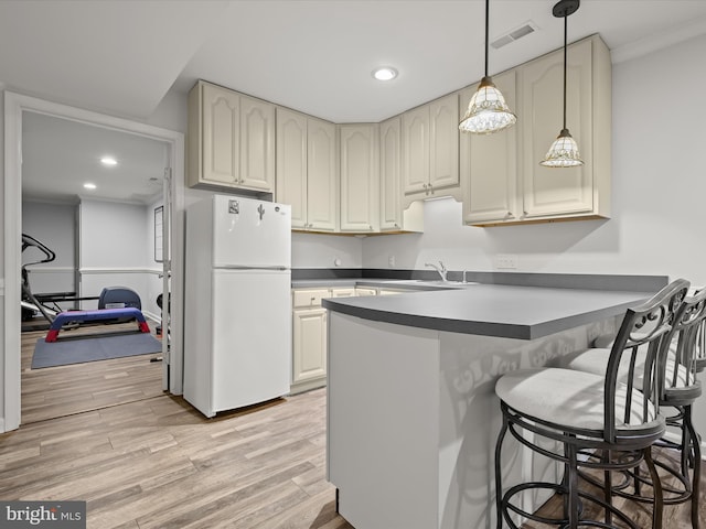 kitchen featuring visible vents, a peninsula, freestanding refrigerator, and light wood-type flooring