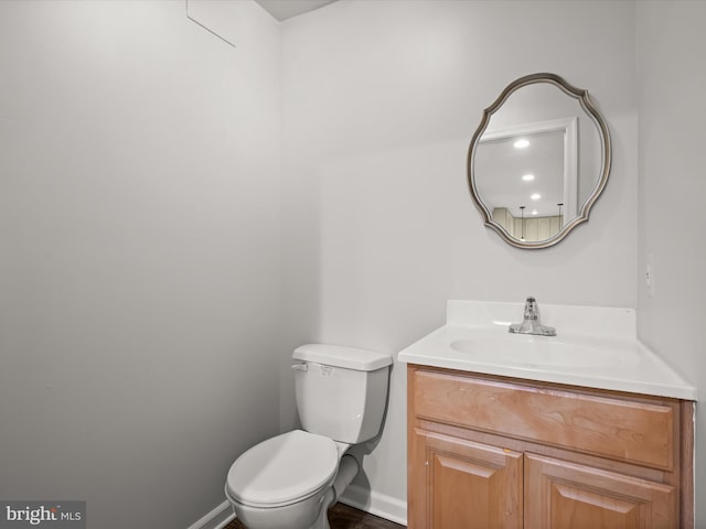 bathroom featuring toilet, vanity, and baseboards