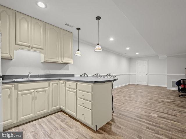 kitchen featuring dark countertops, crown molding, light wood-type flooring, visible vents, and recessed lighting