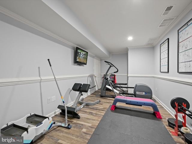 exercise area with baseboards, ornamental molding, wood finished floors, and visible vents