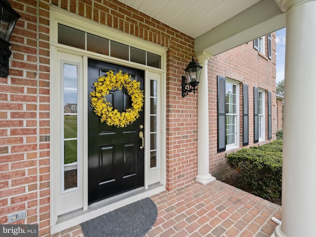 view of exterior entry with brick siding and a porch