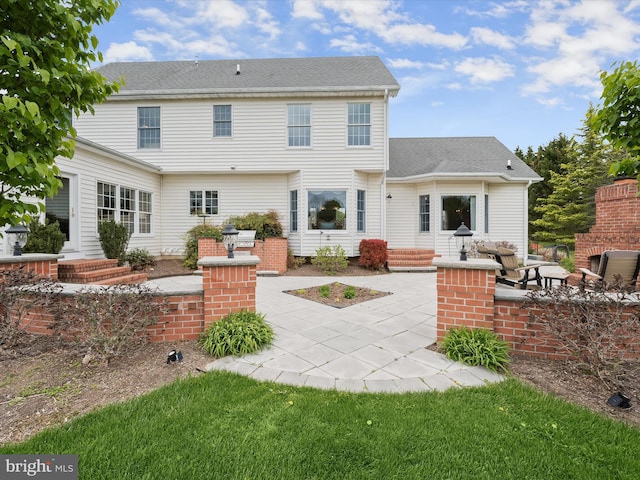 rear view of property featuring roof with shingles and a patio