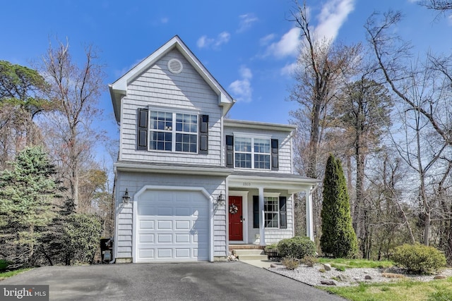 traditional-style home with covered porch, an attached garage, and driveway