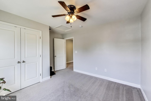 unfurnished bedroom with light carpet, attic access, baseboards, and a closet