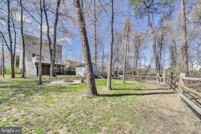 view of yard featuring stairs, an outdoor structure, a fire pit, a storage unit, and a deck