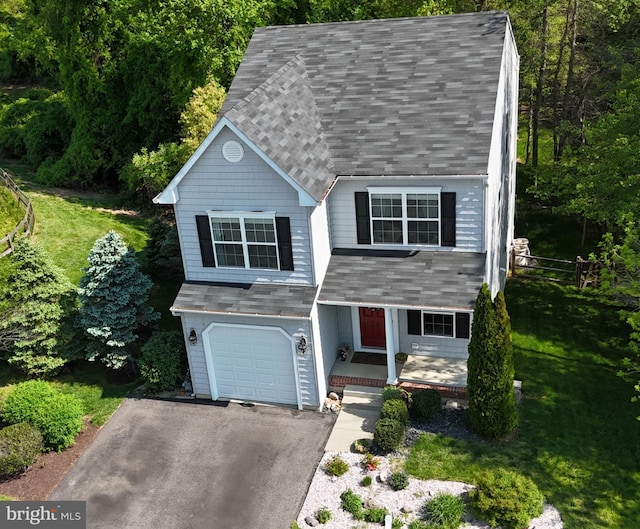 view of front facade featuring roof with shingles, an attached garage, driveway, and a porch