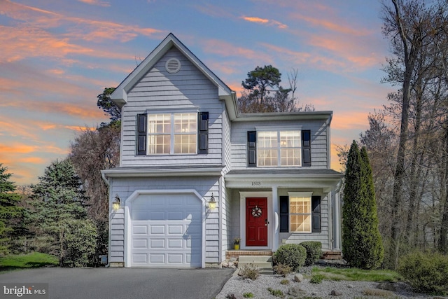 traditional-style house with an attached garage, covered porch, and asphalt driveway