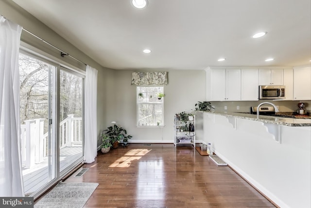 kitchen featuring stainless steel appliances, healthy amount of natural light, light stone counters, white cabinets, and recessed lighting