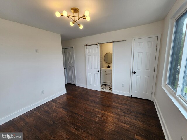 1261 Gallatin St NE, Washington, DC 20017 - unfurnished bedroom with a chandelier, baseboards, dark wood-type flooring, a barn door, and a sink