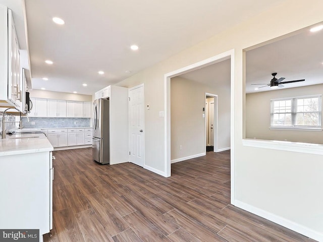 kitchen featuring a sink, light countertops, ceiling fan, stainless steel appliances, and decorative backsplash