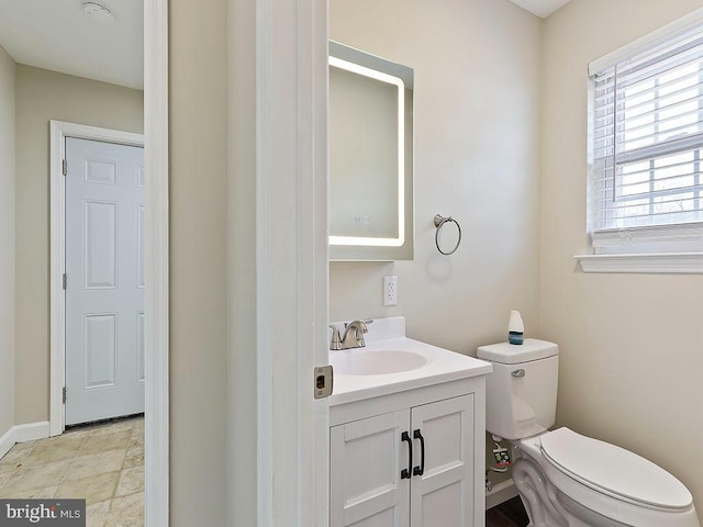 bathroom featuring toilet, vanity, and baseboards