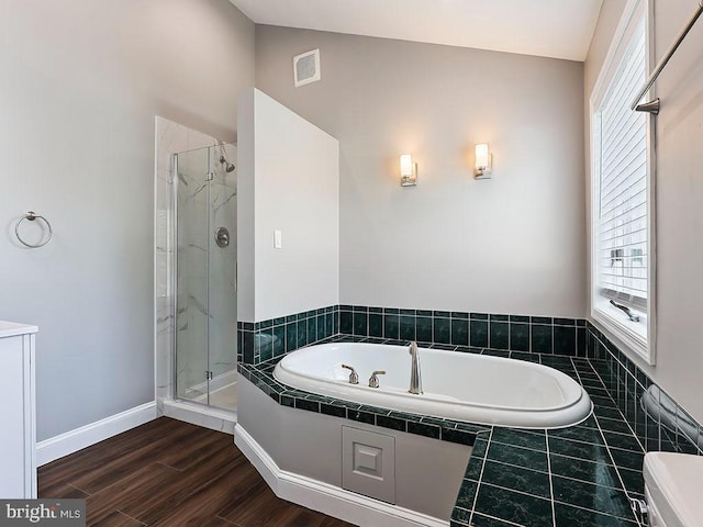 bathroom featuring a shower stall, a bath, visible vents, wood finished floors, and baseboards