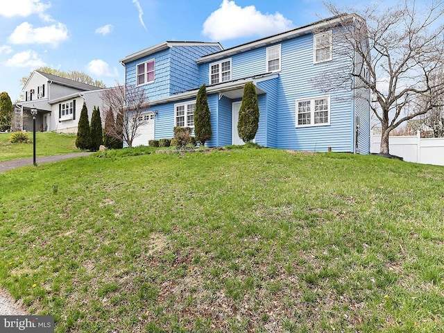 view of front of property with an attached garage, fence, and a front lawn