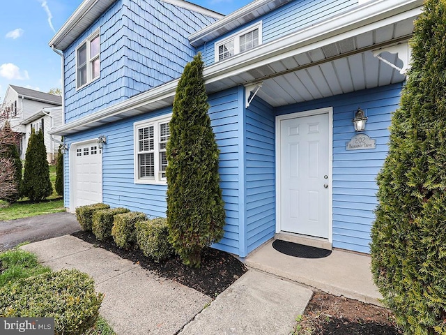 property entrance featuring an attached garage and driveway