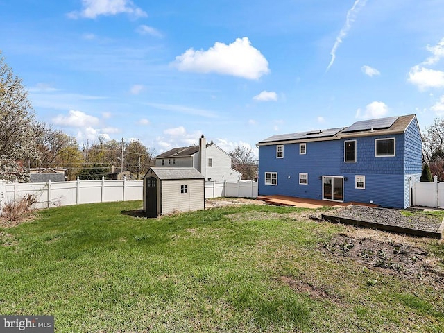 back of house featuring an outbuilding, a storage shed, a yard, a fenced backyard, and a deck