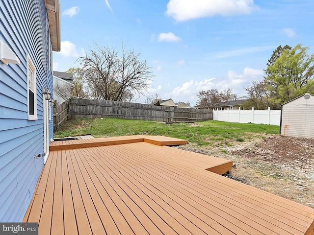 deck with a shed, a fenced backyard, an outdoor structure, and a lawn