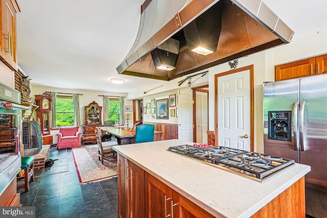 kitchen with brown cabinets, open floor plan, extractor fan, appliances with stainless steel finishes, and a kitchen island