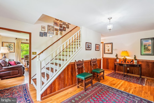 stairs featuring wood walls, wood finished floors, and wainscoting