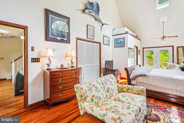 bedroom featuring a closet, french doors, access to outside, high vaulted ceiling, and wood finished floors
