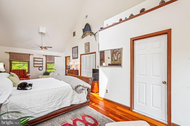 bedroom with light wood-type flooring, visible vents, and high vaulted ceiling