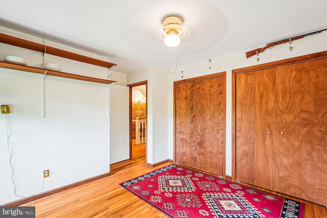 unfurnished bedroom with baseboards, multiple closets, and wood finished floors